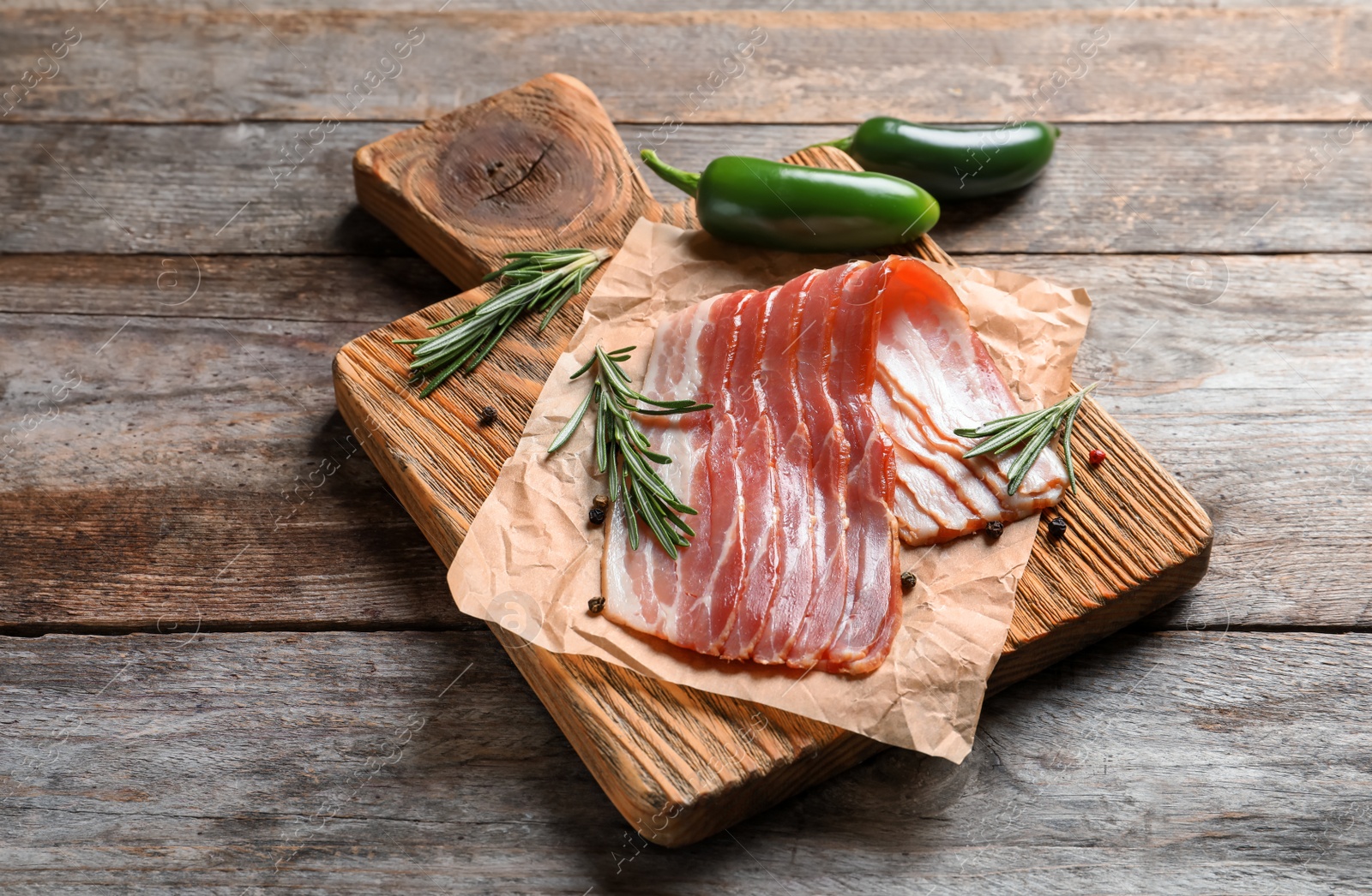 Photo of Board with raw bacon on wooden background