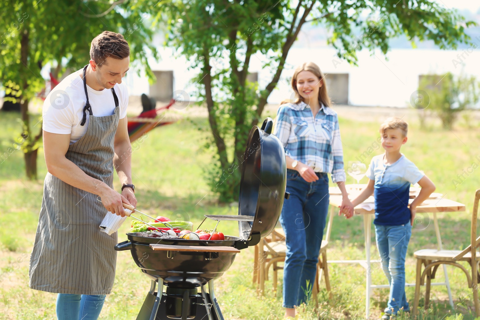 Photo of Happy family having barbecue with modern grill outdoors