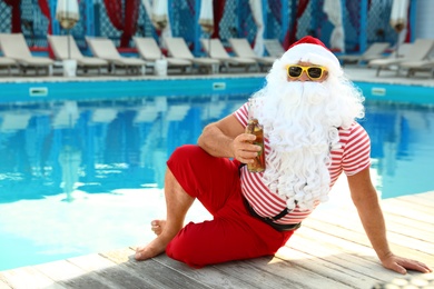 Authentic Santa Claus with bottle of beer near pool at resort