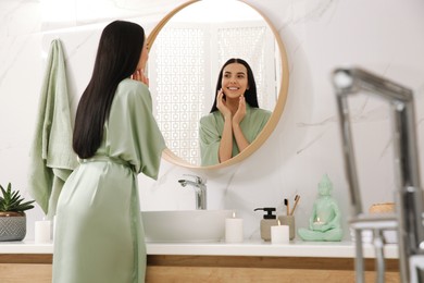 Photo of Beautiful young woman near mirror in bathroom