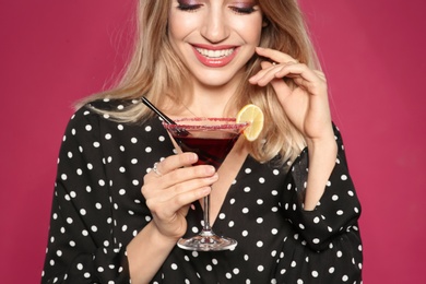 Beautiful young woman with glass of martini cocktail on color background, closeup