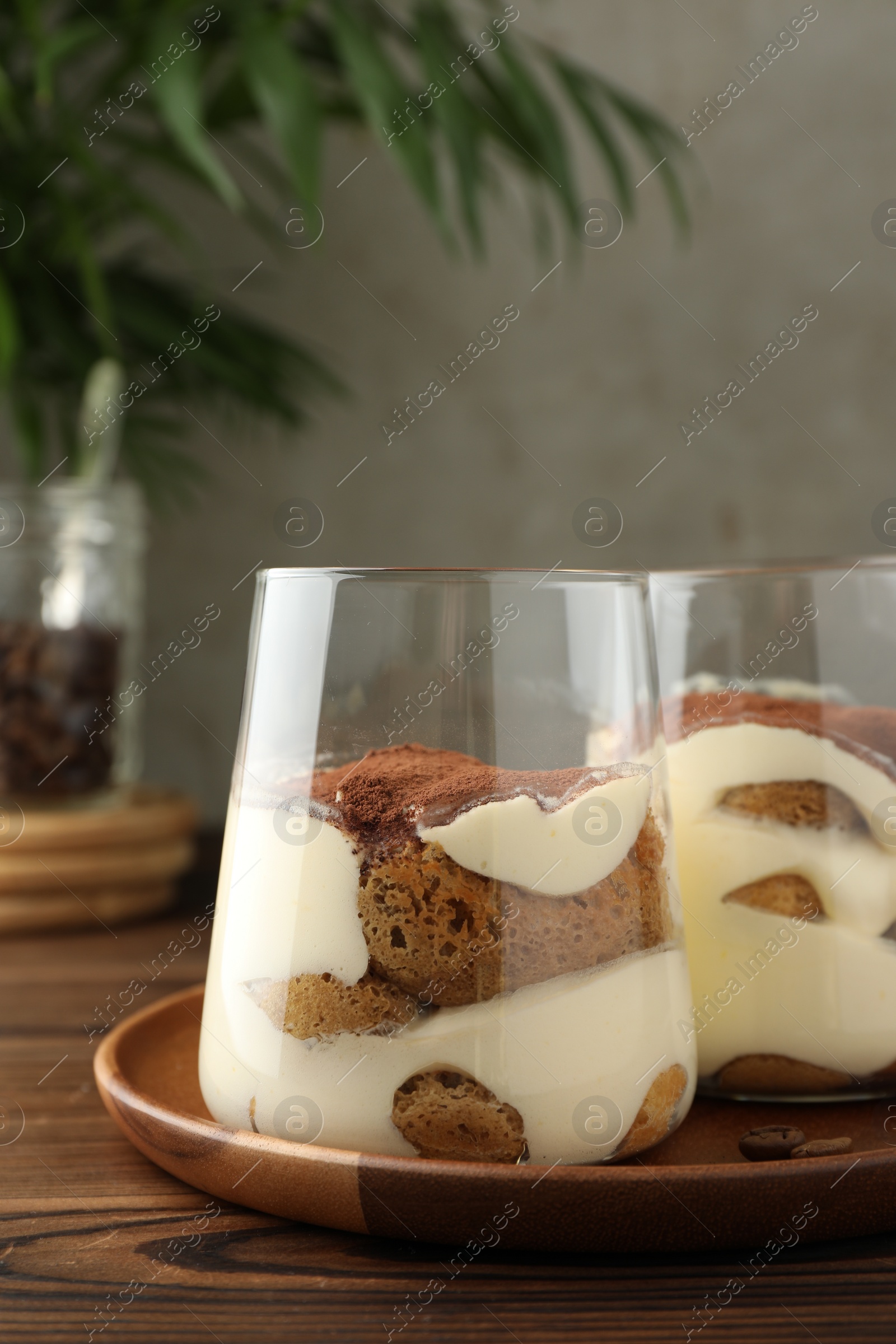 Photo of Delicious tiramisu in glasses on wooden table, closeup