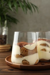 Delicious tiramisu in glasses on wooden table, closeup