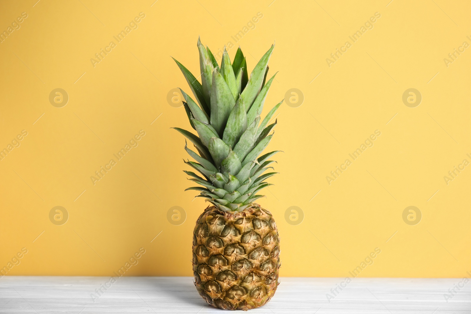 Photo of Fresh ripe juicy pineapple on white wooden table