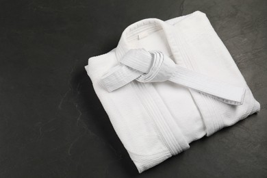 Photo of White karate belt and kimono on gray background, top view. Space for text