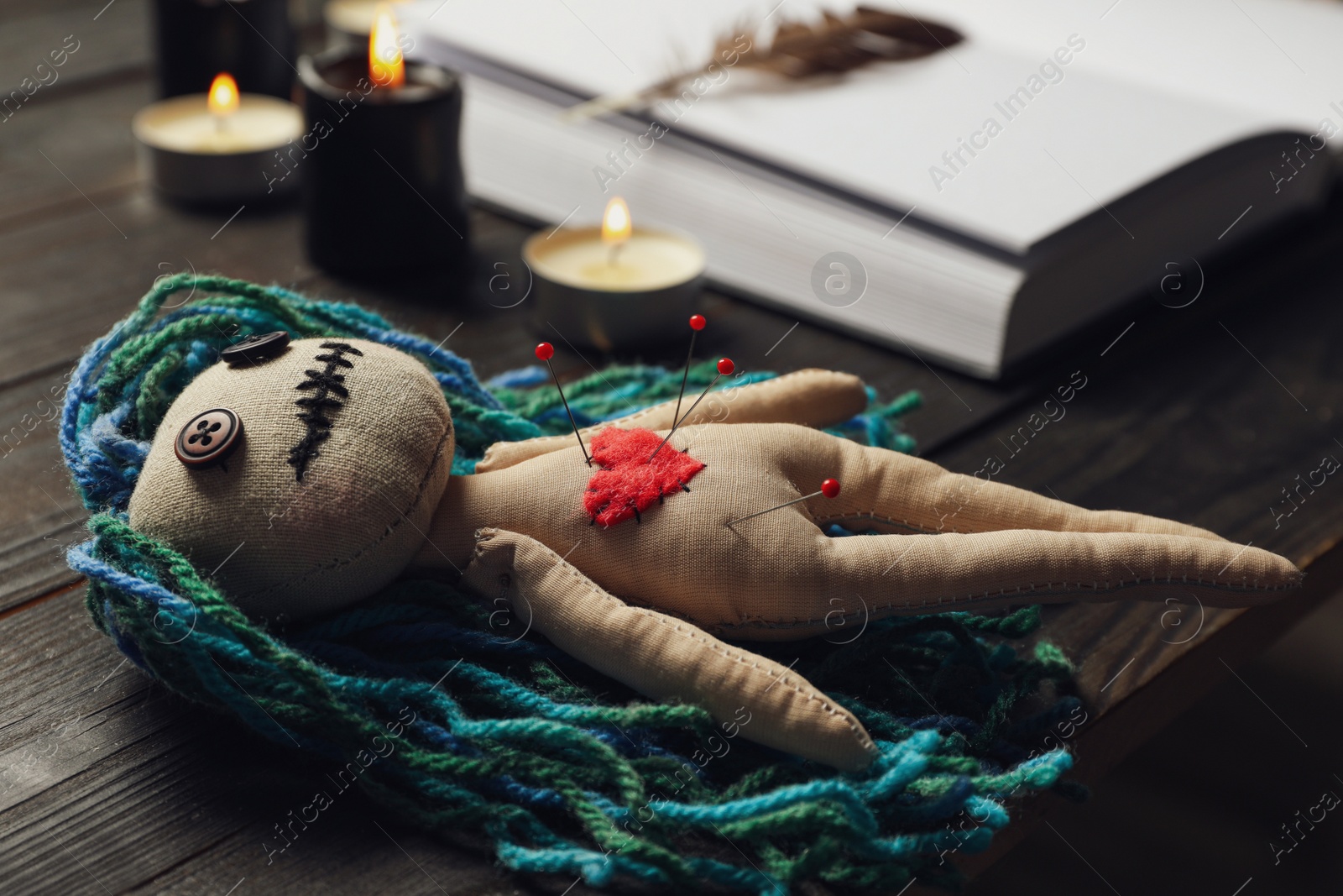 Photo of Voodoo doll with pins on dark wooden table, closeup