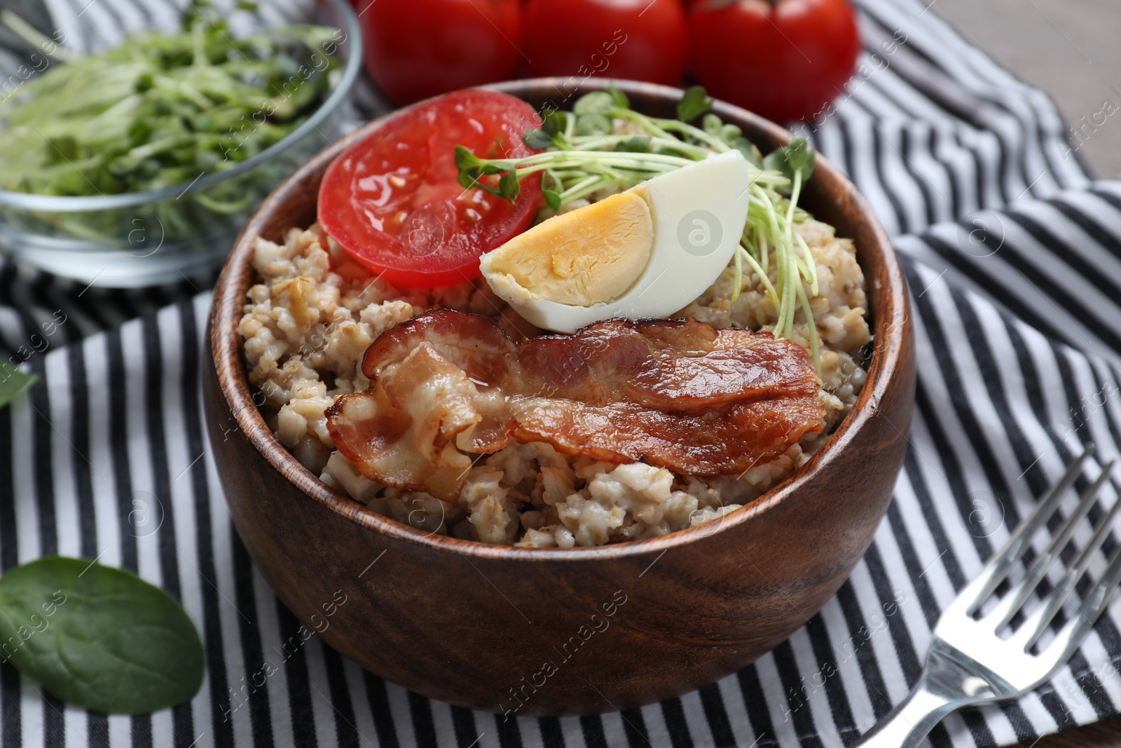 Photo of Delicious boiled oatmeal with egg, bacon and tomato on table, closeup