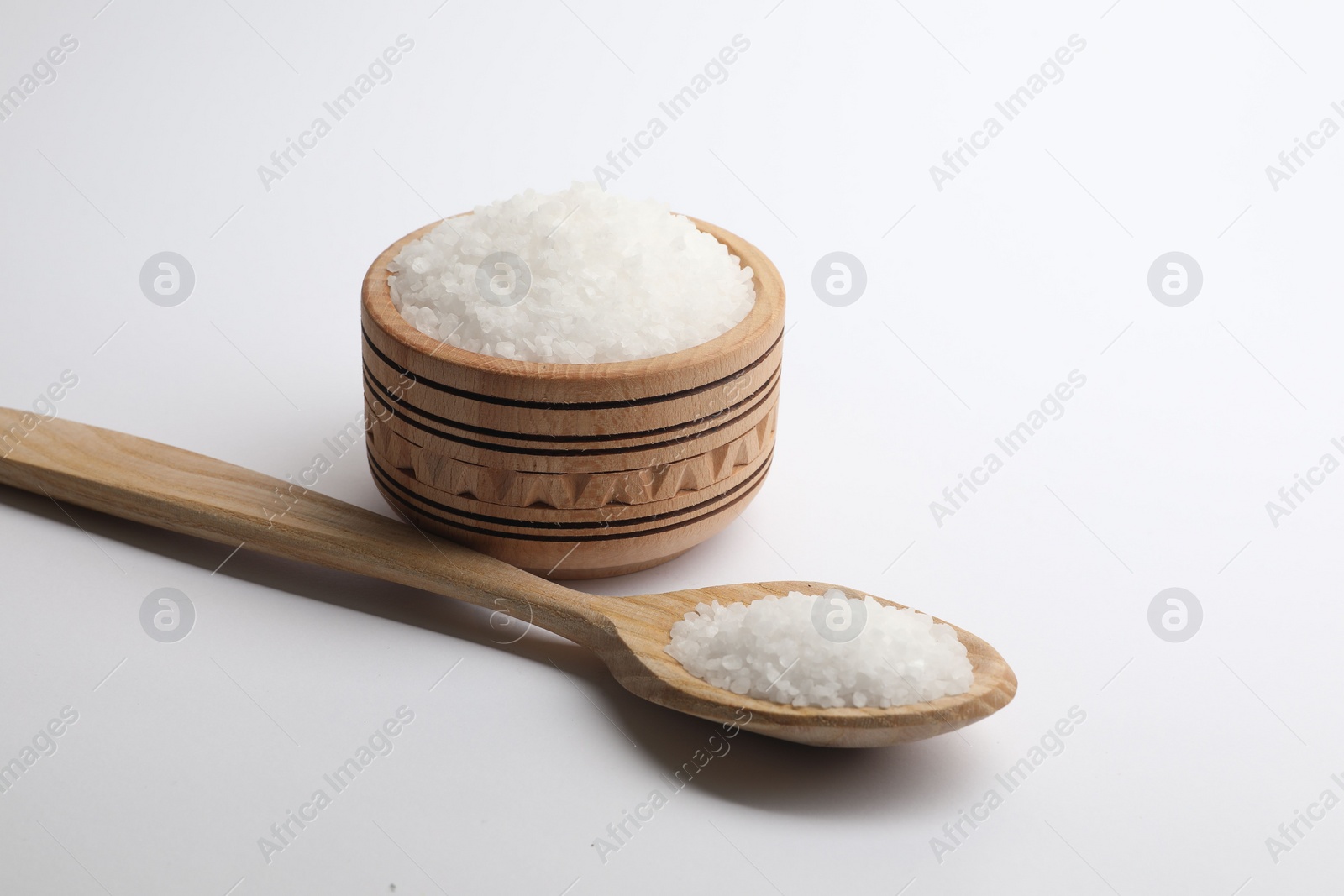 Photo of Natural salt in wooden spoon and bowl on white background