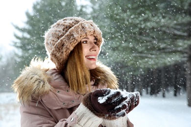 Beautiful woman holding snow in winter forest