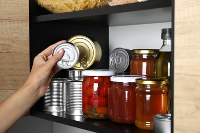 Photo of Woman taking jar of honey from shelf indoors, closeup. Food donation