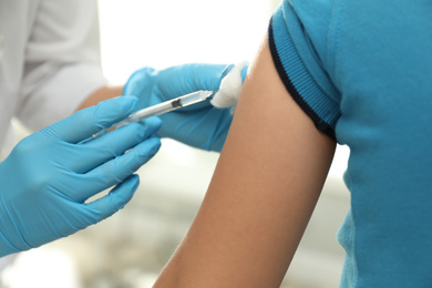 Doctor vaccinating little child in clinic, closeup