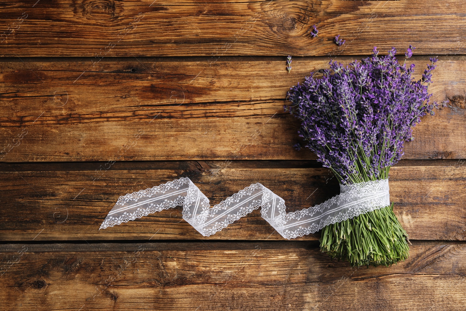 Photo of Beautiful fresh lavender bouquet with lace ribbon on wooden background, top view