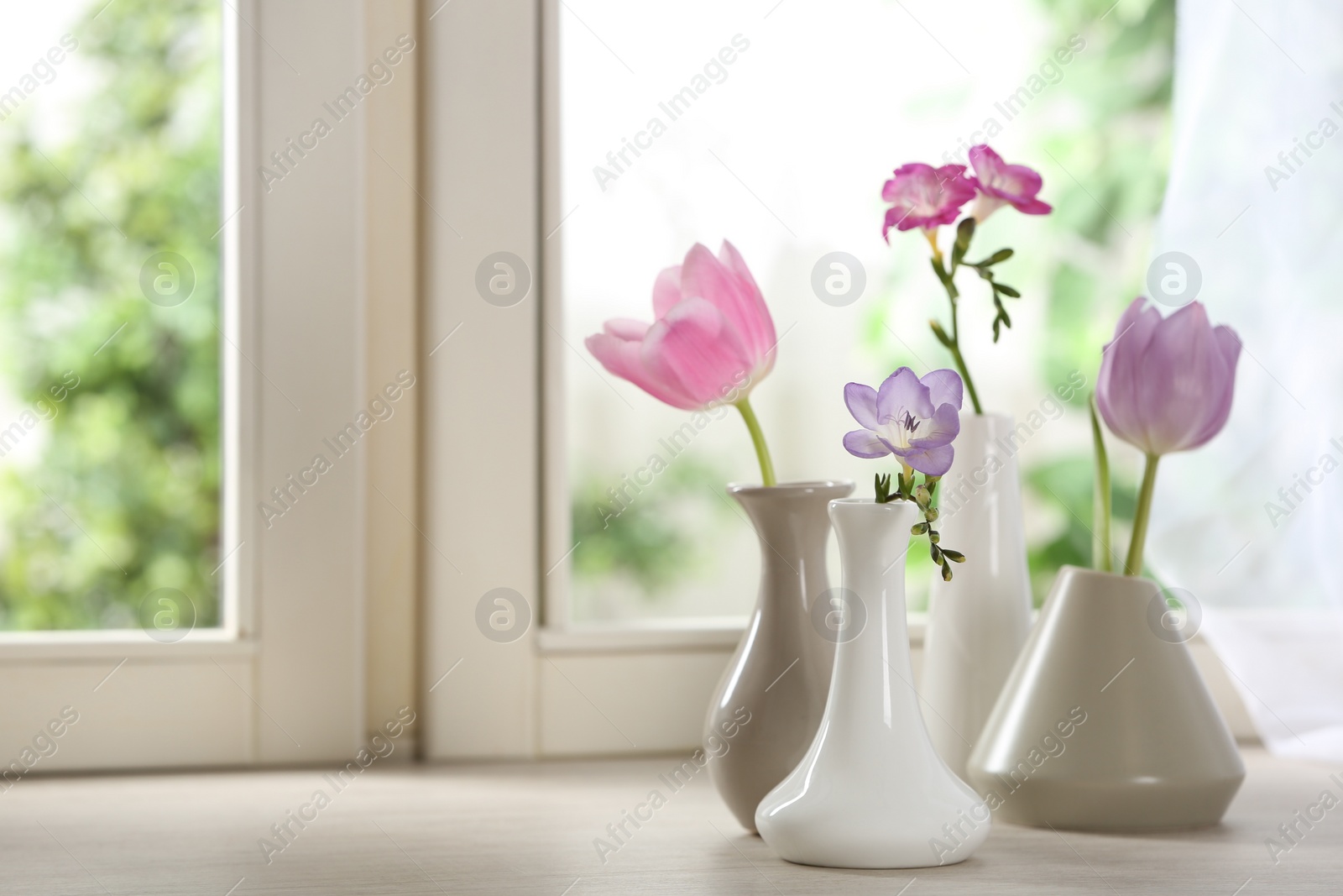 Photo of Beautiful fresh flowers on window sill indoors. Space for text