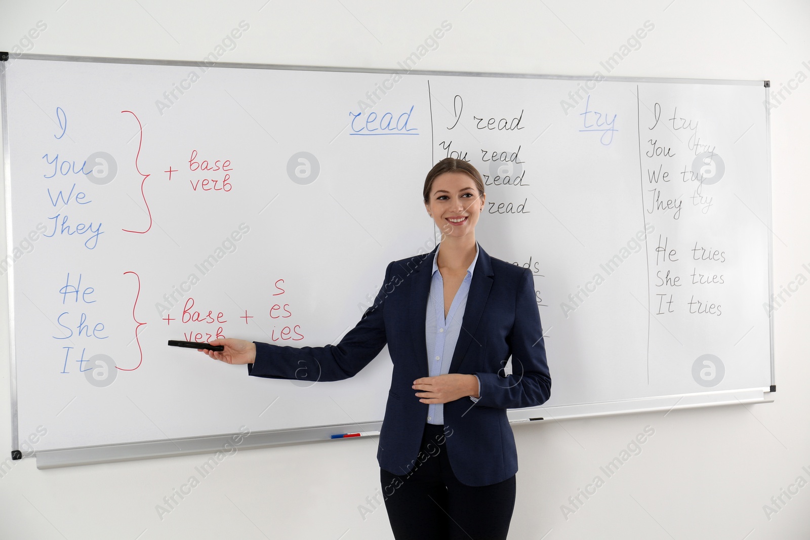 Photo of English teacher giving lesson near whiteboard in classroom