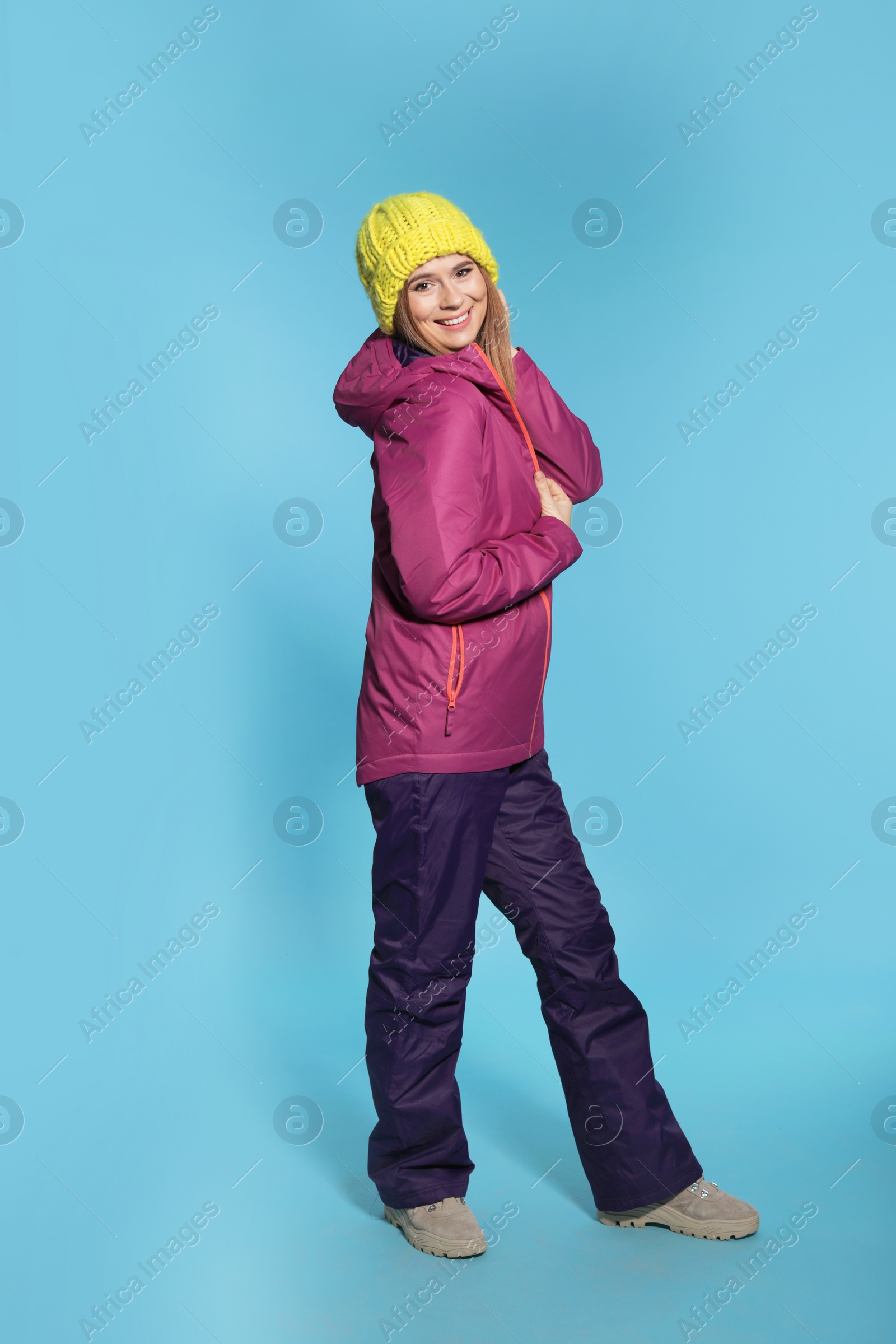 Photo of Young woman wearing warm clothes on color background. Ready for winter vacation