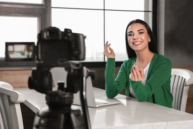 Photo of Young blogger with laptop recording video on camera at cafe