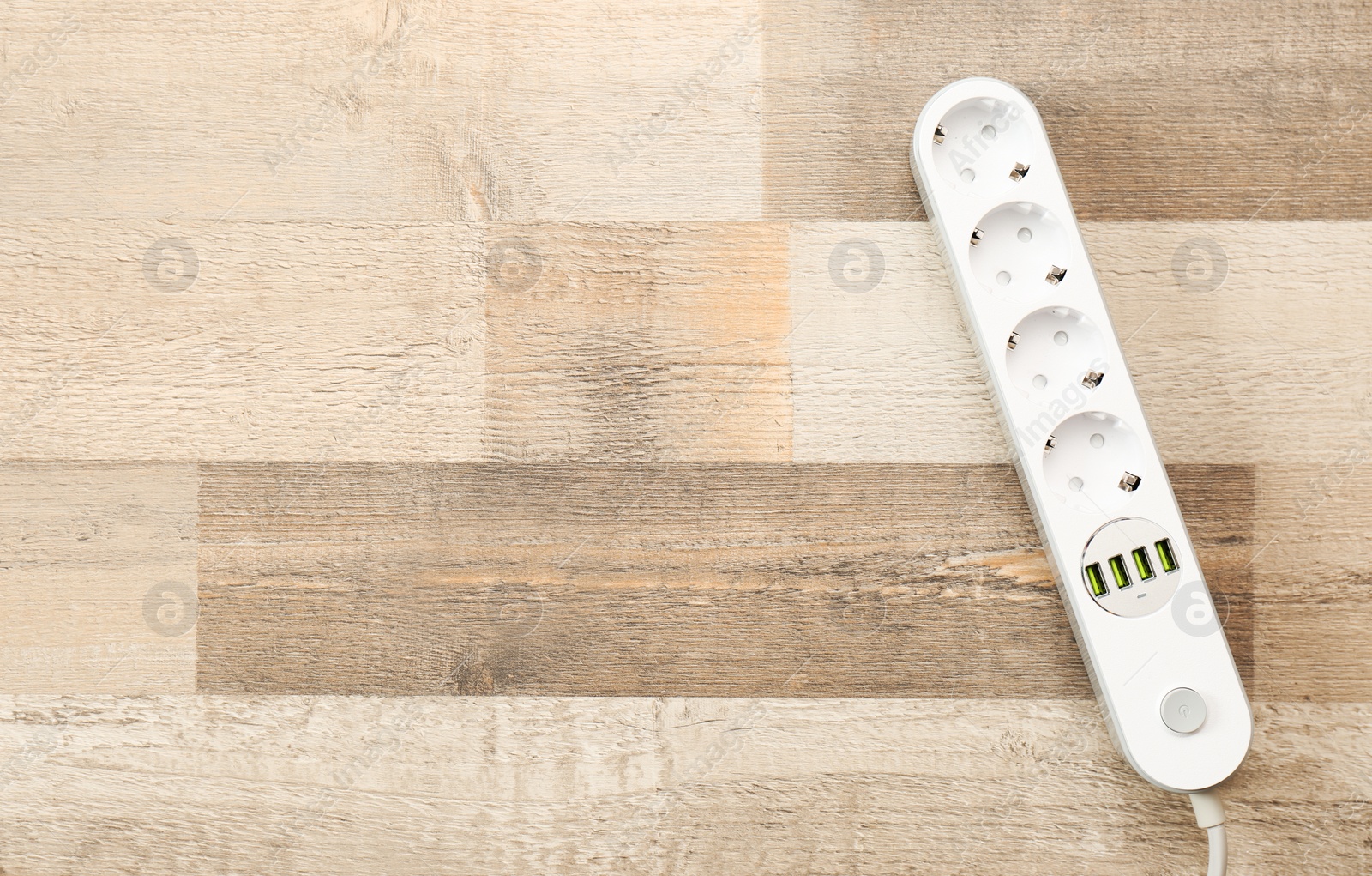 Photo of Extension cord on wooden floor, top view with space for text. Electrician's equipment