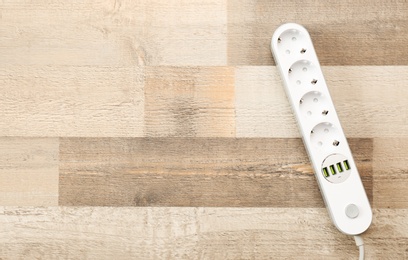 Extension cord on wooden floor, top view with space for text. Electrician's equipment