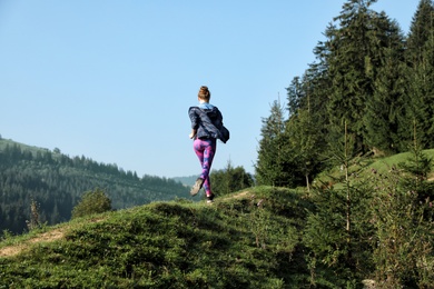 Photo of Young woman running on mountain trail in summer