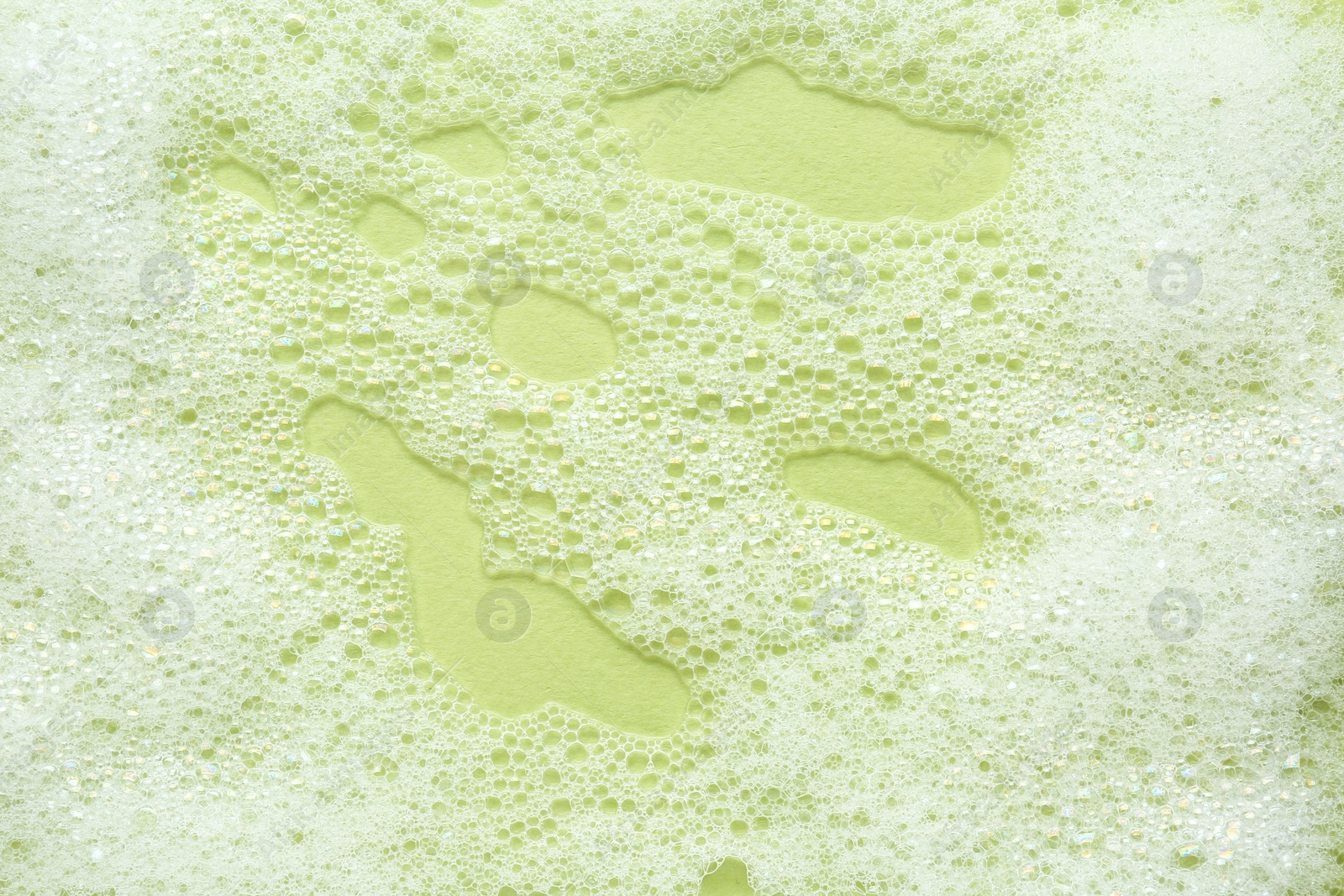 Photo of Fluffy bath foam on light green background, top view