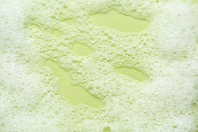 Photo of Fluffy bath foam on light green background, top view