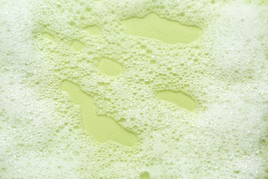 Fluffy bath foam on light green background, top view