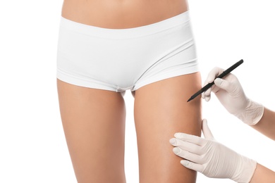 Doctor holding marker near young woman's leg isolated on white, closeup. Plastic surgery concept