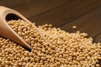 Photo of Wooden scoop with soy on table, closeup