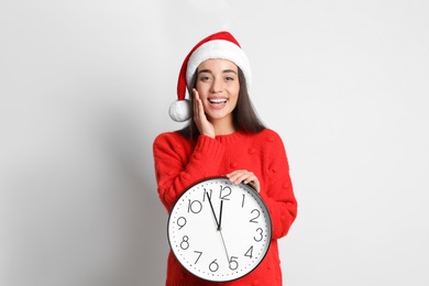 Woman in Santa hat with clock on white background. Christmas countdown