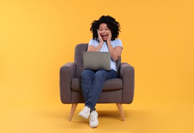 Photo of Emotional young woman with laptop sitting in armchair against yellow background