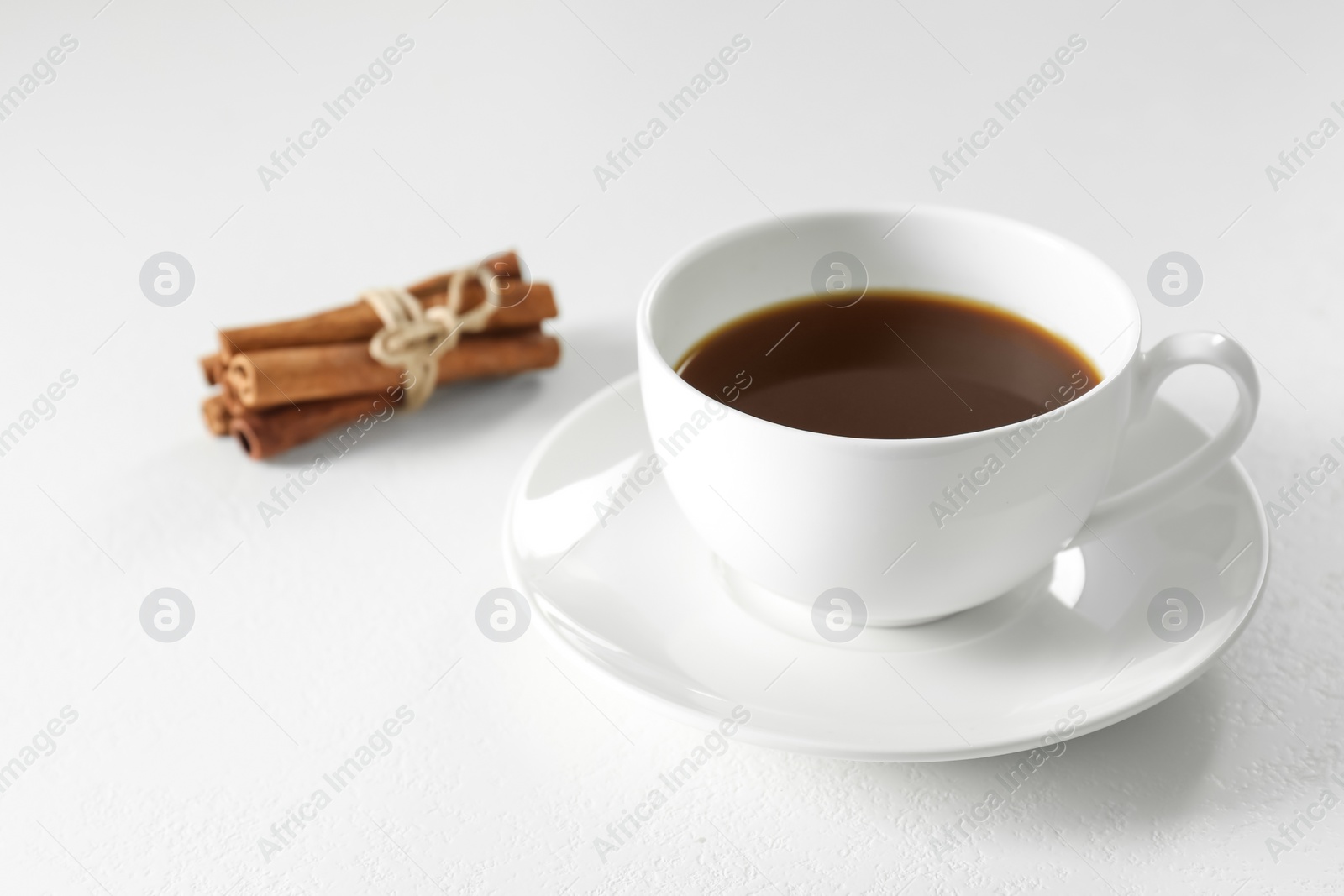 Photo of Turkish coffee. Freshly brewed beverage and cinnamon on white table, closeup