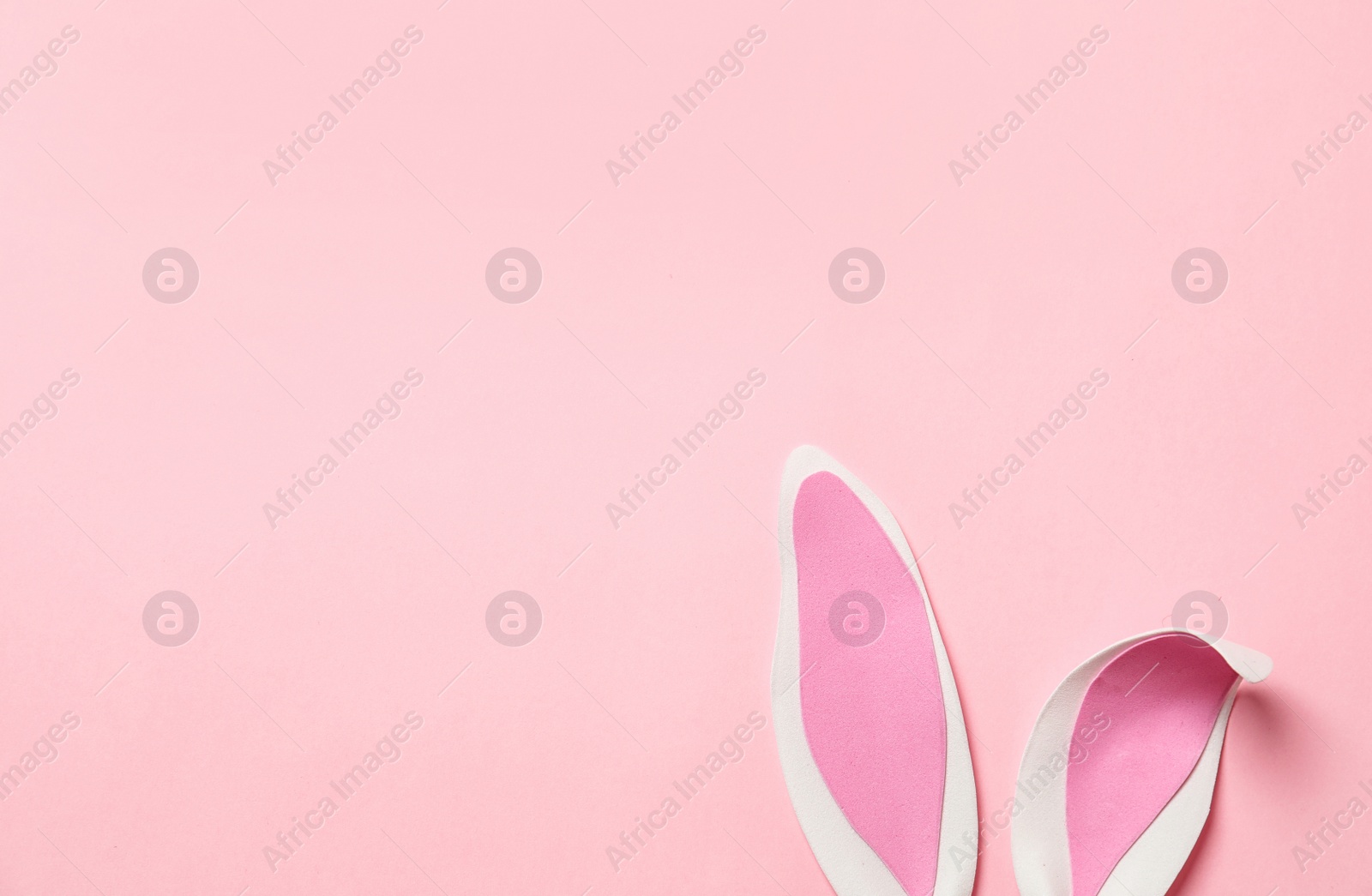 Photo of Funny Easter bunny ears on color background, top view with space for text