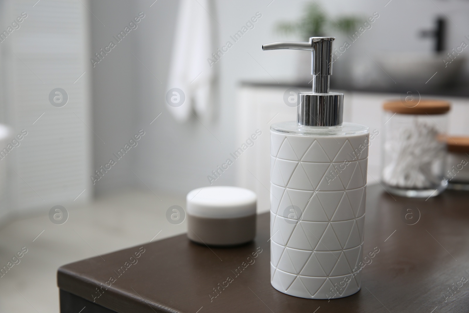 Photo of Dispenser of liquid soap on wooden table in bathroom. Space for text