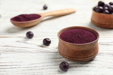 Photo of Bowl with acai powder on wooden table