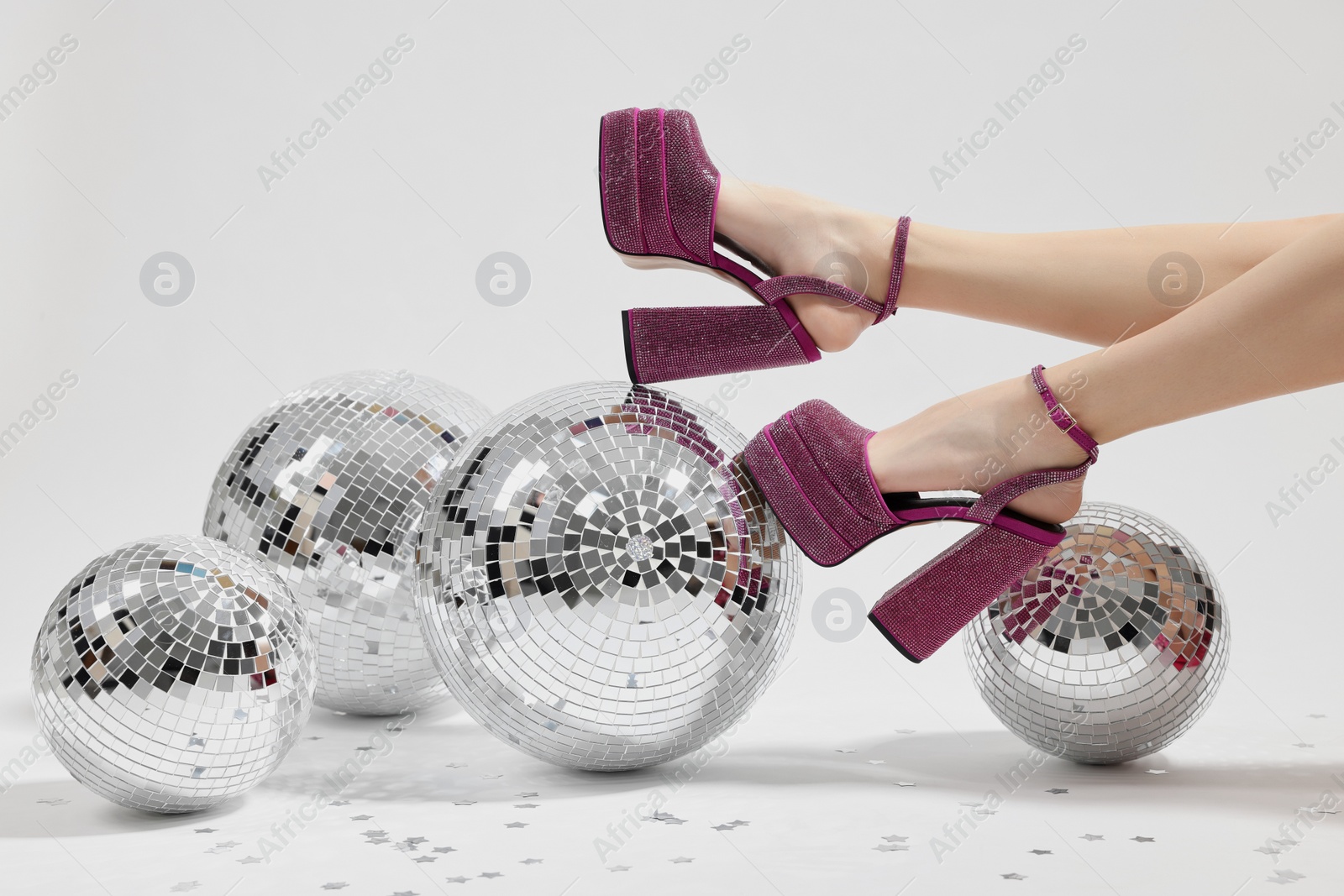 Photo of Woman in pink high heeled shoes and disco balls on white background, closeup