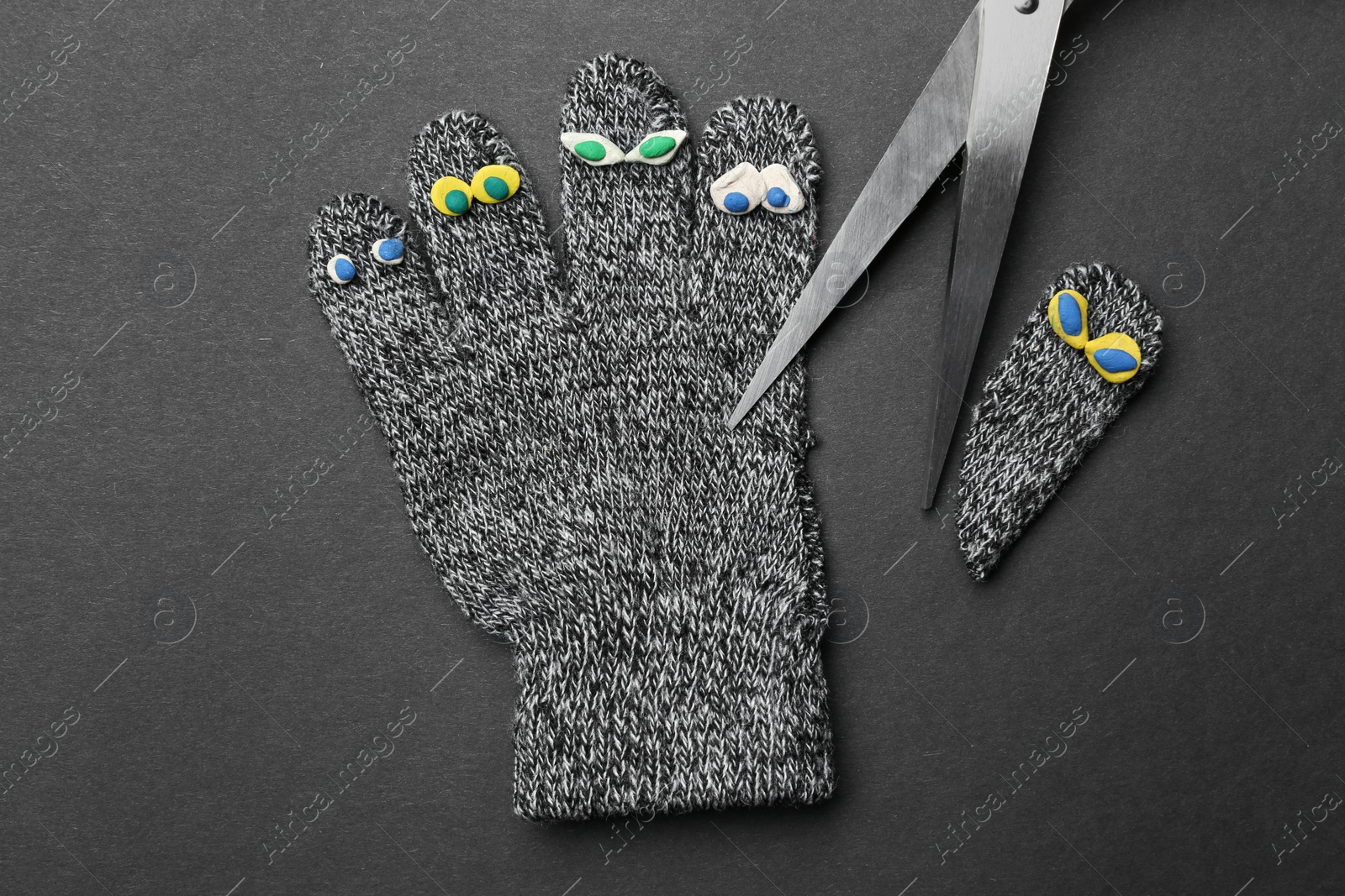 Photo of Divorce concept. Knitted glove and scissors on dark background, flat lay