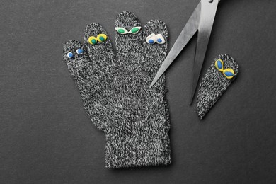 Photo of Divorce concept. Knitted glove and scissors on dark background, flat lay