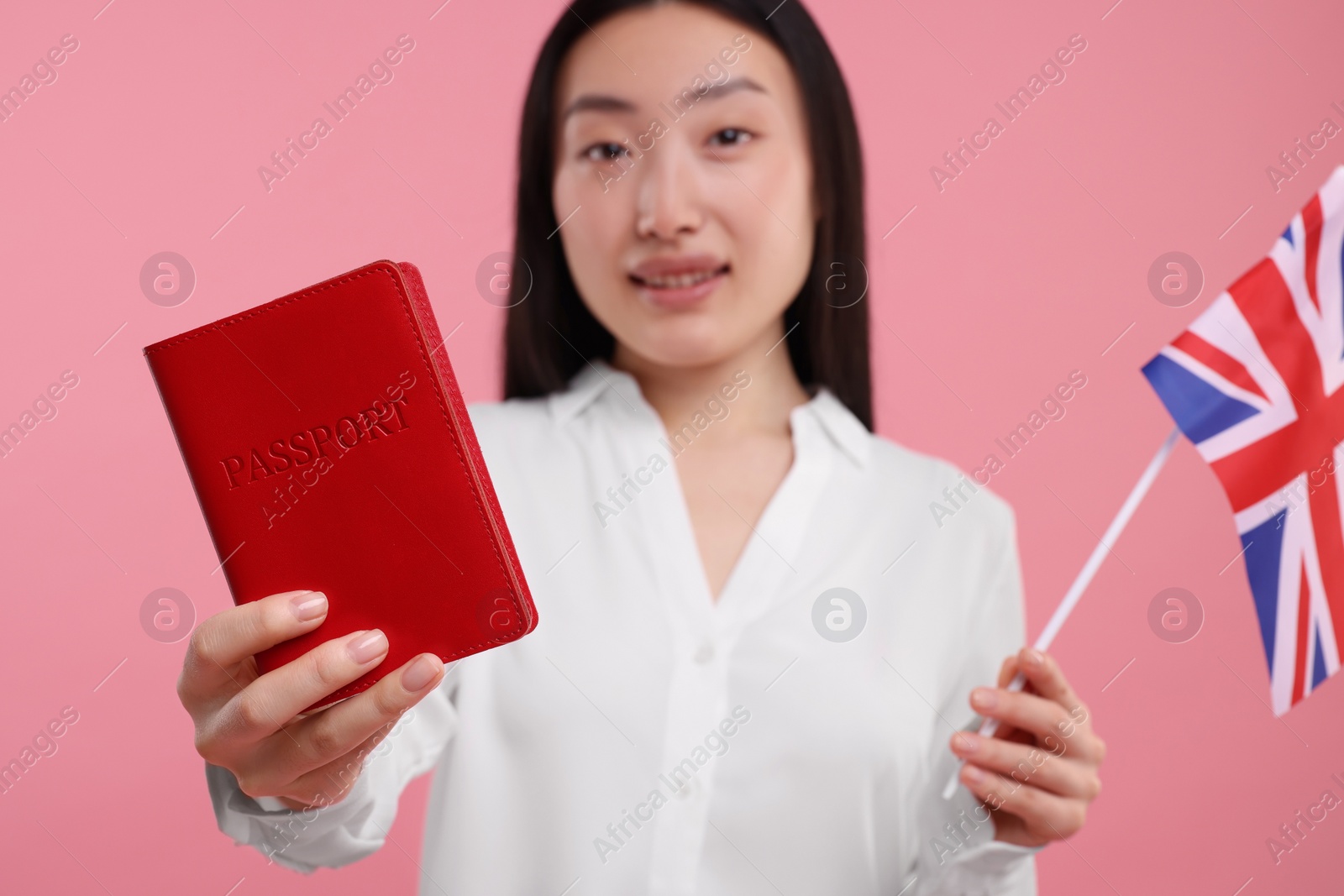 Photo of Immigration to United Kingdom. Happy woman with passport and flag on pink background, selective focus