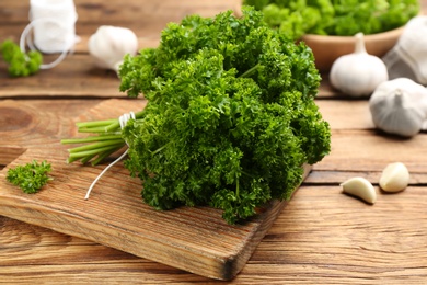 Fresh curly parsley and garlic on wooden table