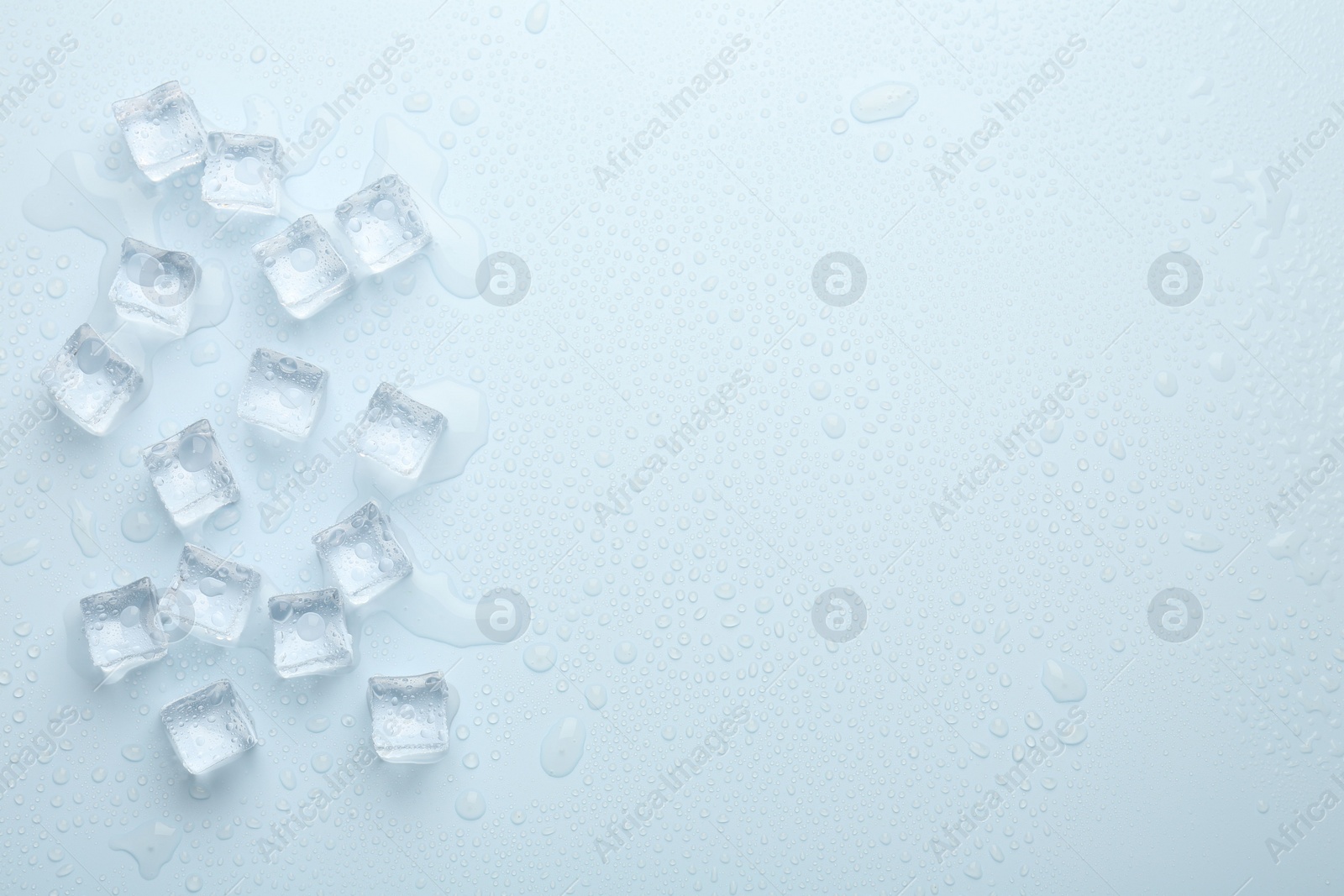 Photo of Crystal clear ice cubes on light blue background, flat lay. Space for text