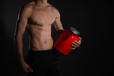 Photo of Athletic man with big red jar on black background, closeup. Doping concept