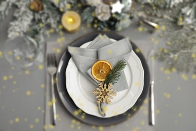 Image of Christmas place setting for festive dinner on grey table, flat lay. Bokeh effect