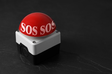 Image of Red SOS button on black table. Space for text