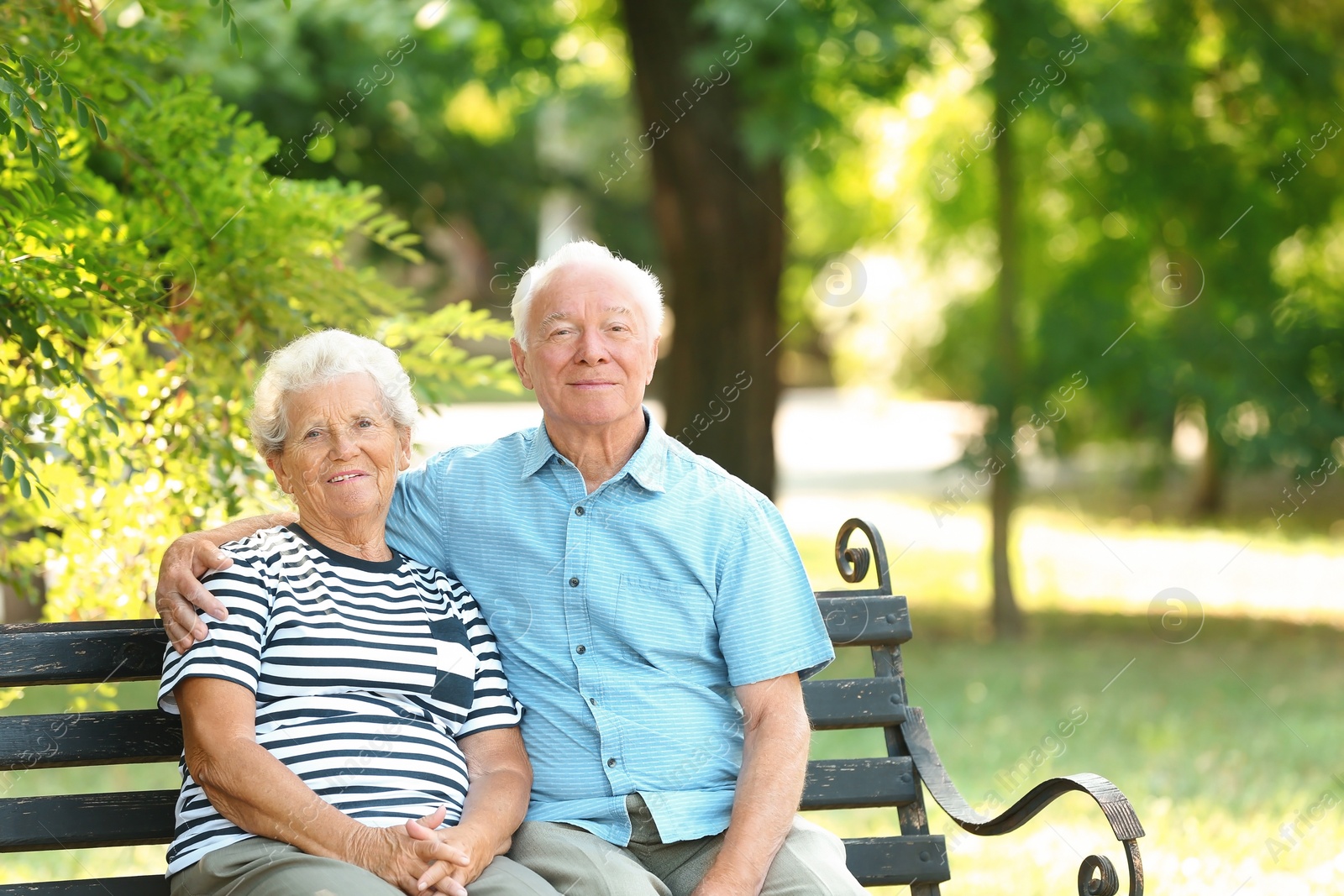 Photo of Elderly couple resting on bench in park