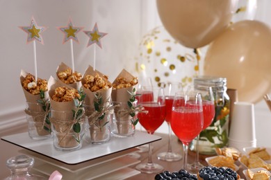 Photo of Delicious party treats and drinks on wooden table indoors