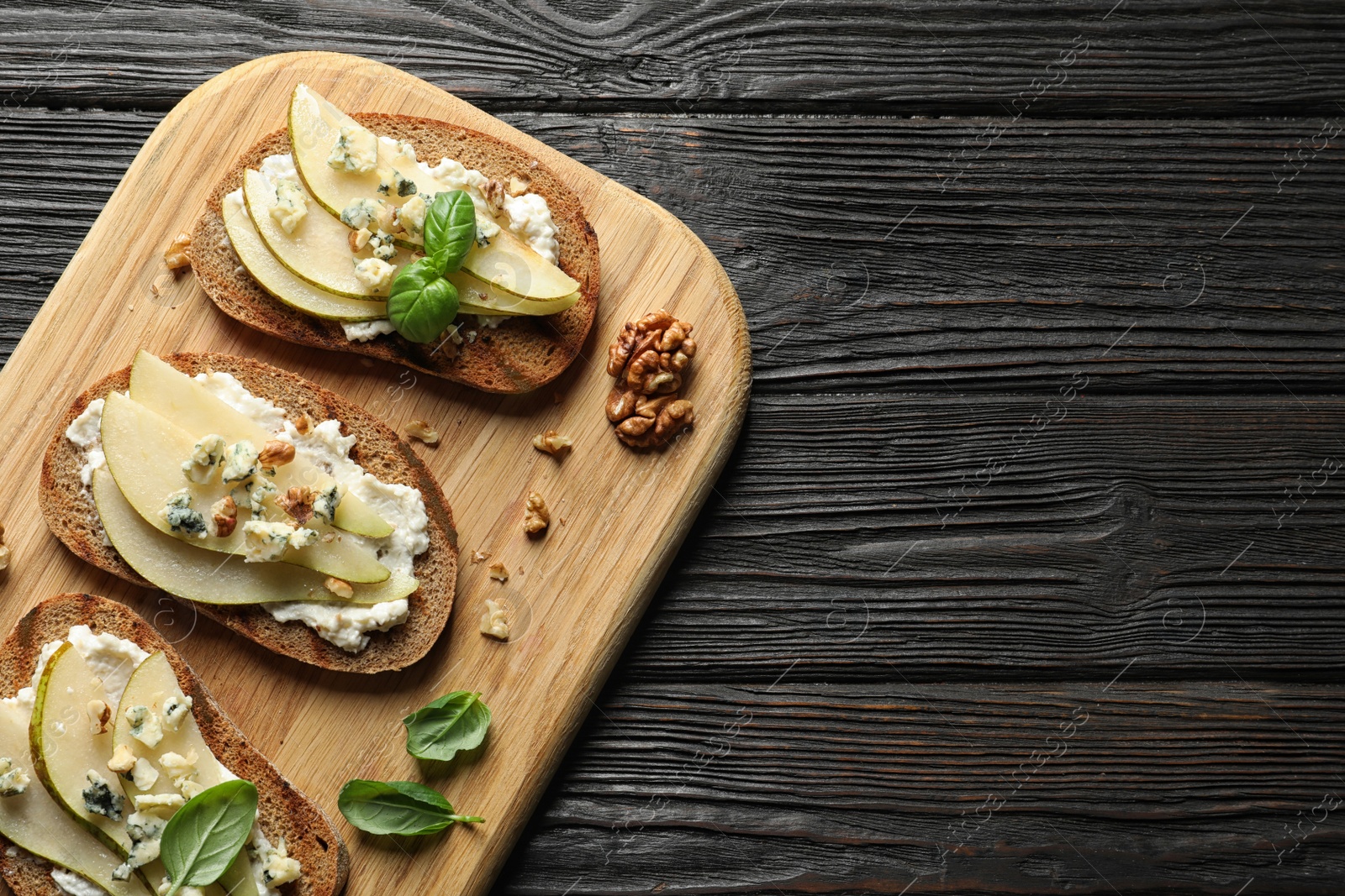 Photo of Wooden board with delicious pear bruschettas on table, flat lay. Space for text