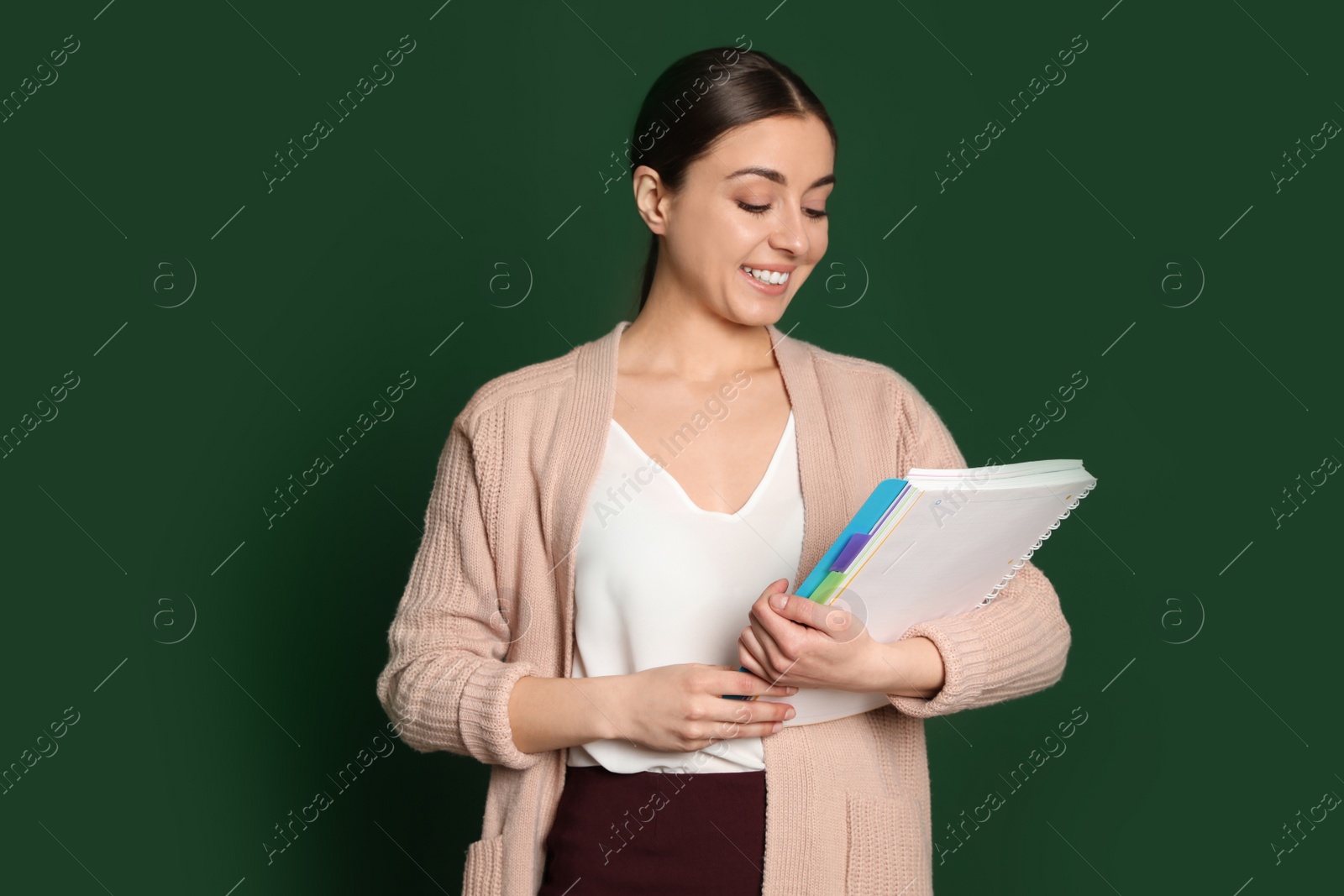 Photo of Portrait of young teacher with notebook on green background