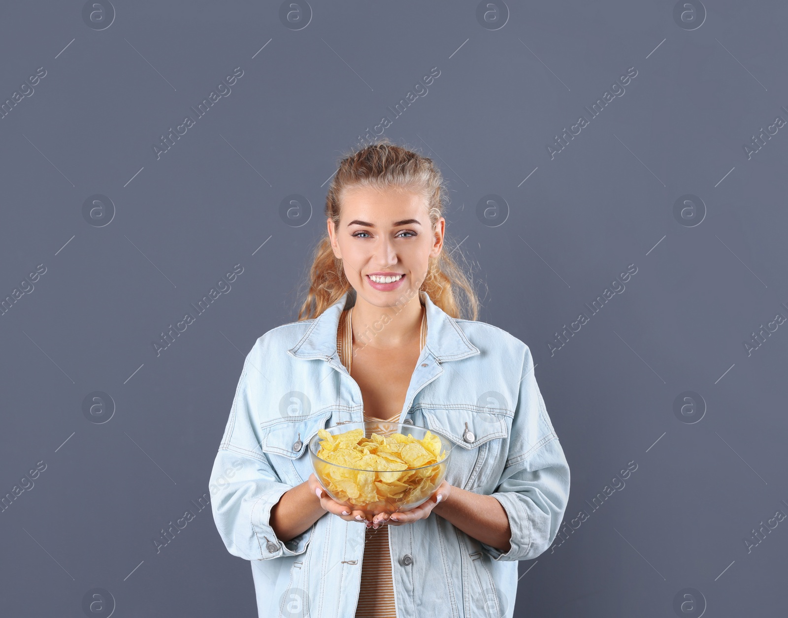 Photo of Woman with bowl of potato chips on grey background