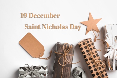 Image of 19 December Saint Nicholas Day. Beautiful gift boxes with tags on white background, top view