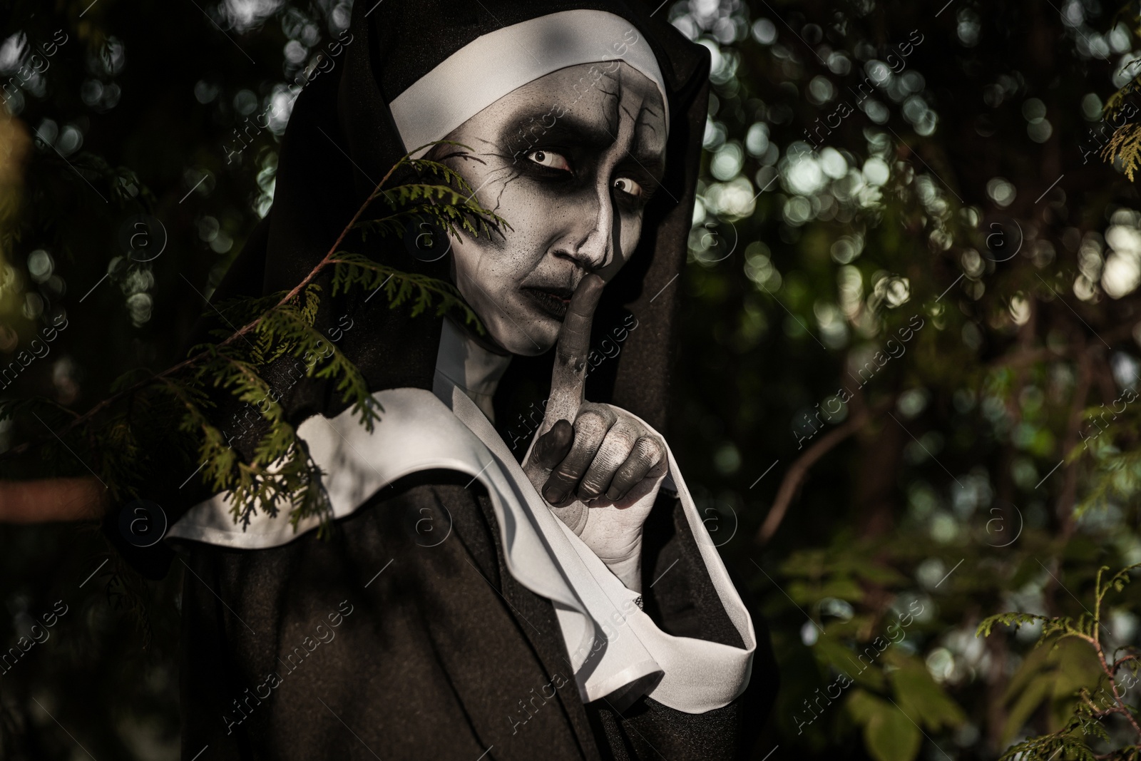 Photo of Portrait of scary devilish nun near tree outdoors. Halloween party look